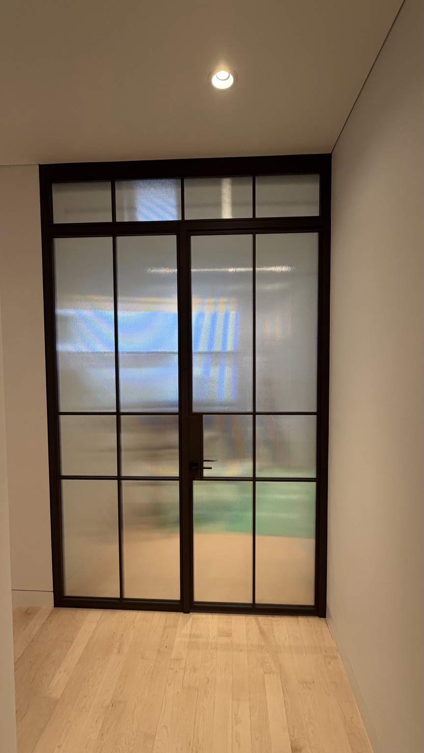 Tall black framed door and transom with privacy glass