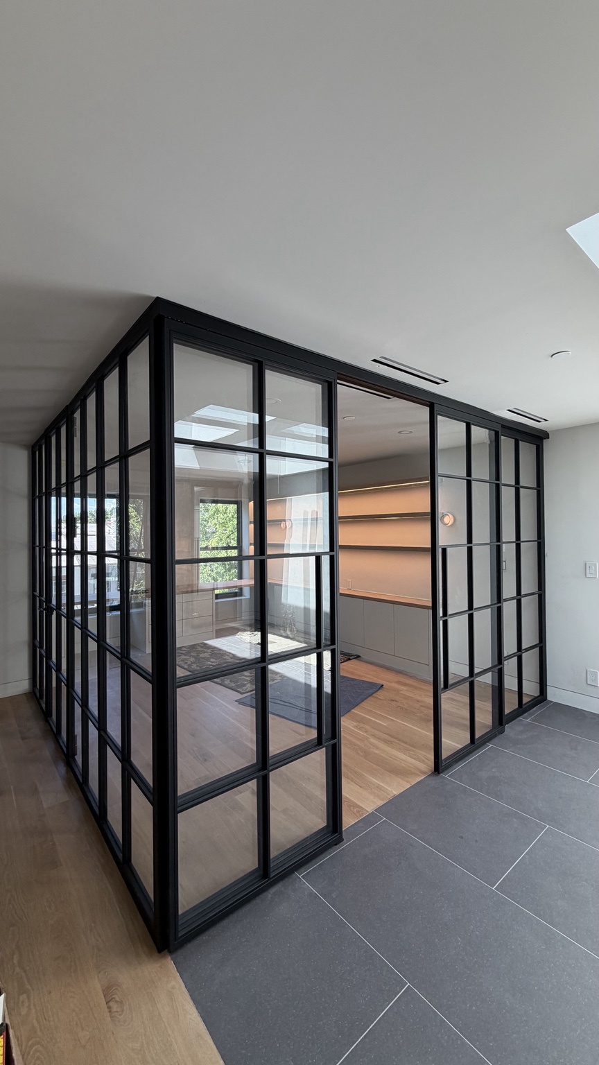 Custom floor-to-ceiling black framed glass room enclosure installed by YAVIR NY LLC